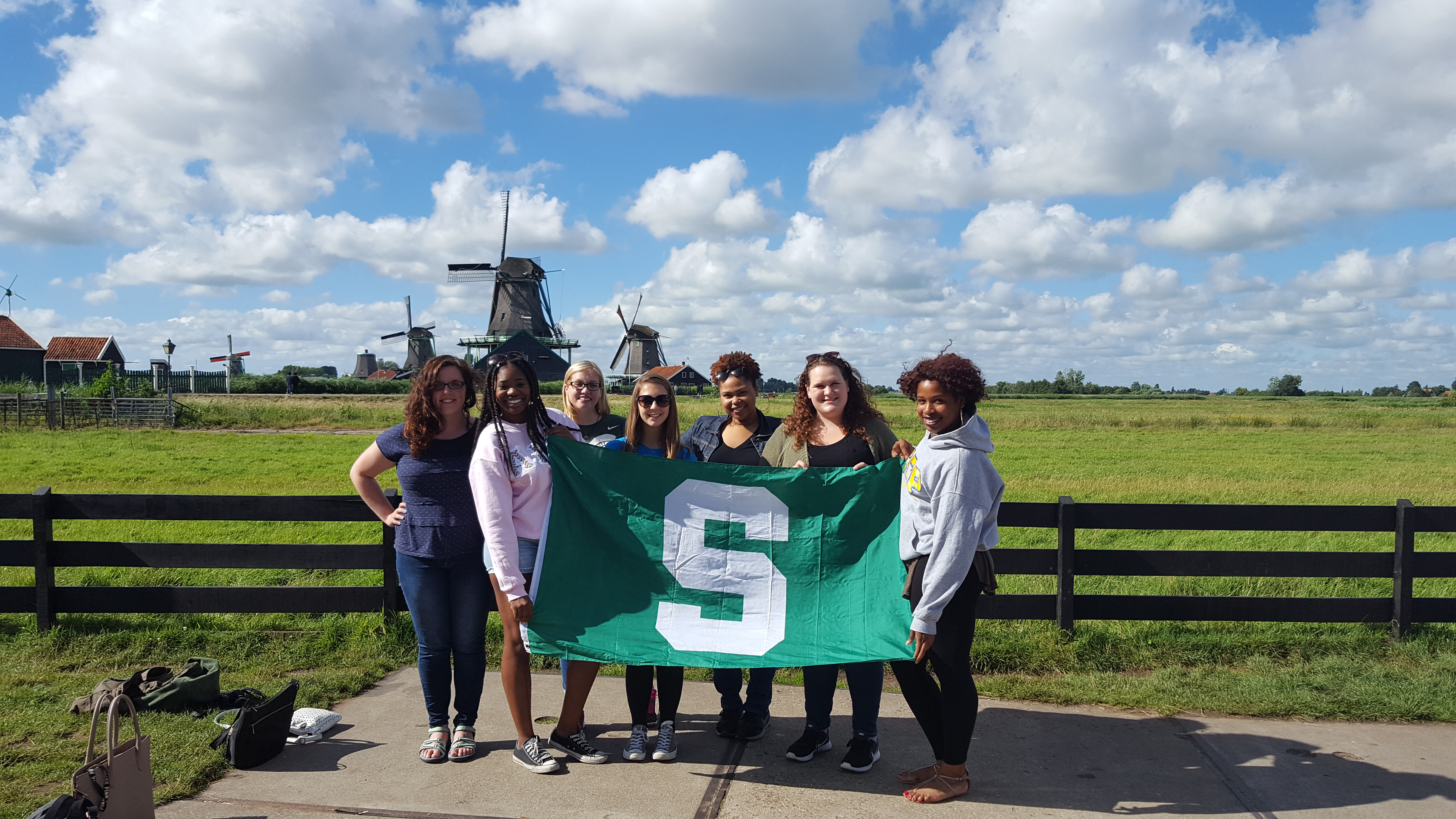 London study abroad student group standing in field holding MSU spartan flag