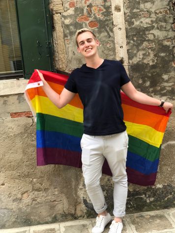 Jonathon Walkotten posing with a rainbow pride flag